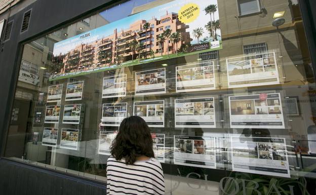 Uan joven mira las ofertas de pisos en una inmobiliaria./