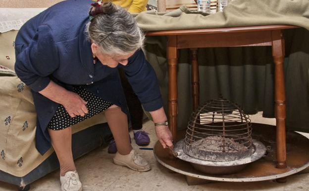 Una vecina muestra el brasero de picón que tiene en su mesa camilla. /