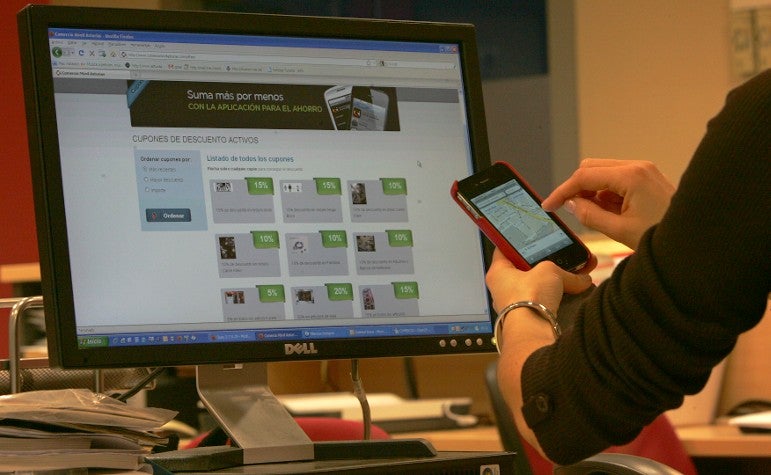 Una mujer consulta en la web y en su teléfono móvil la información sobre la nueva iniciativa de la Unión de Comerciantes de Gijón. :: JOSÉ SIMAL/