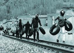 Un grupo de huelguistas camina por la vía del tren, entre Figaredo y Ujo, portando neumáticos para colocar una barricada. :: JAVIER BAULUZ/