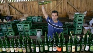 Un echador escancia sidra ante botellas de los diferentes lagares presentes en el certamen. :: CITOULA/