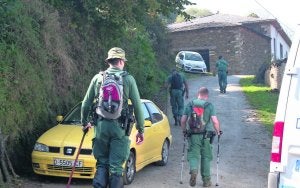 Cuatro agentes, pertrechados para la montaña, caminan hacia la casa familiar de Tomás. :: J. M. AZCÁRATE/