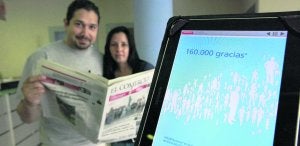 Dos lectores con un ejemplar del diario en papel y, en primer término, una tableta con la versión digital. ::
JORGE PETEIRO/