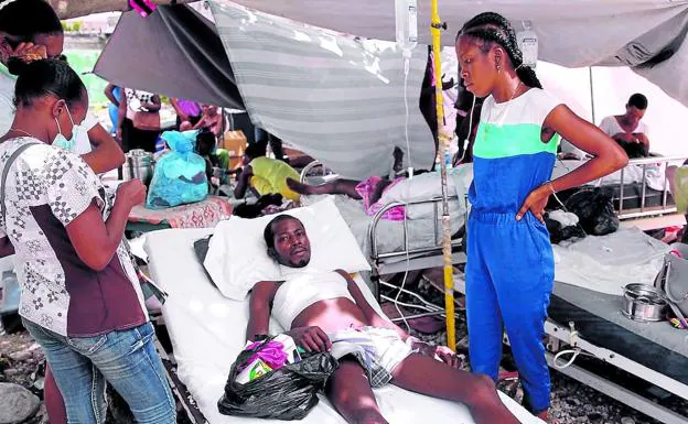 Un herido es asistido en una tienda de campaña improvisada levantado junto a las instalaciones del hospital general de Los Cayos, muy dañado por el terremoto./EFE